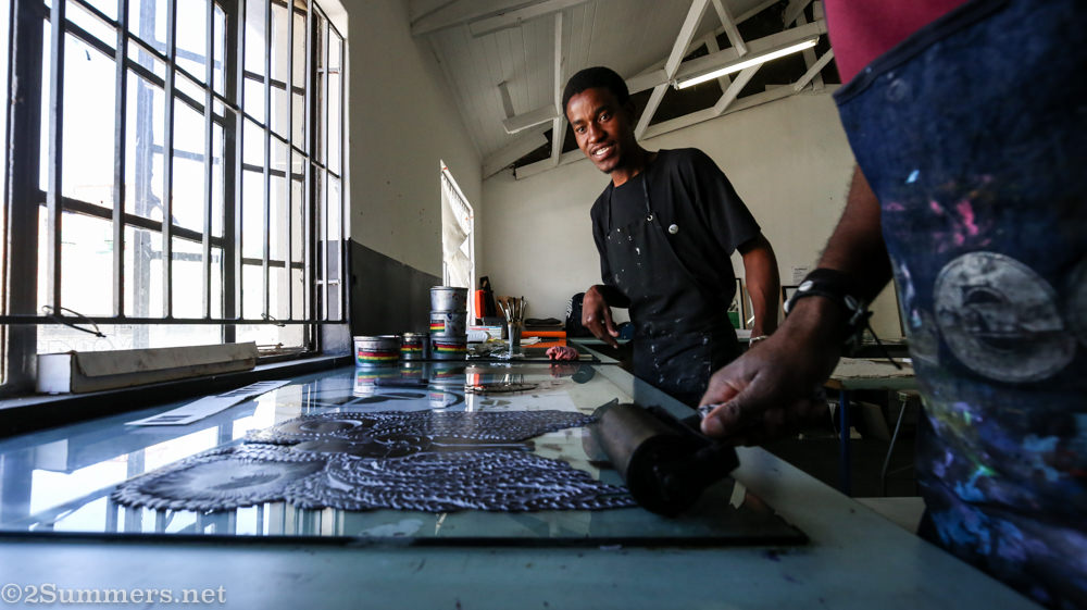 Sanele applies ink to the linocut