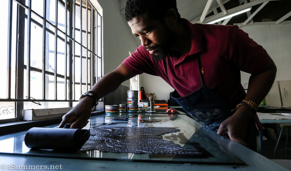 Sanele applies ink to the linocut.