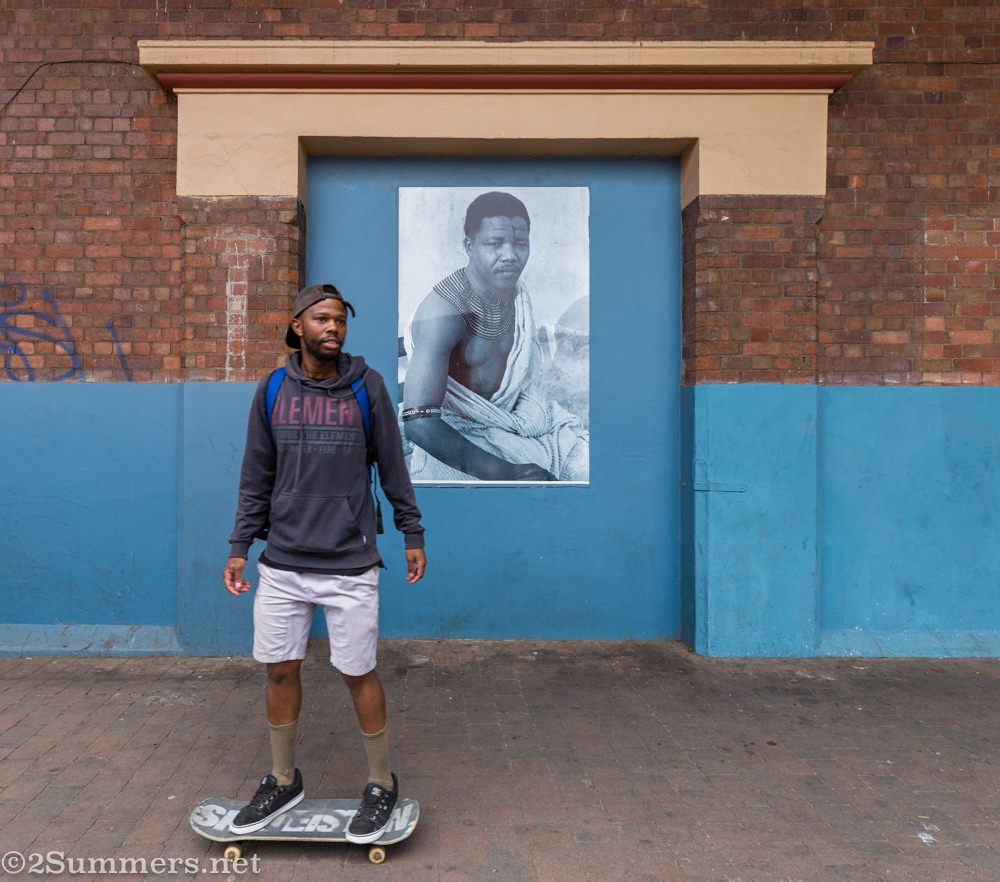 Ayanda skating past the Nelson Mandela portrait at Museum Africa