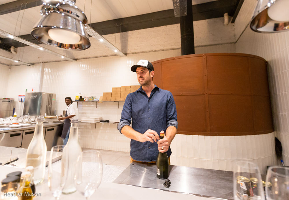 Shane Holt opening a bottle of wine at Coalition Pizza.