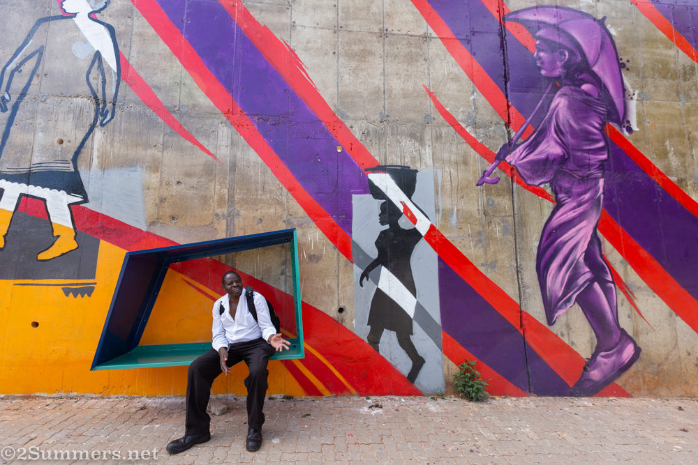 Man sits on a bench at the Louis Botha S-bend mural