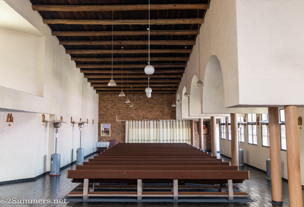 Around the nave are three asymmetrical galleries with long rows of benches facing toward the pulpit. Flo pointed out that the design is very elegant but also built with simple, economical materials – like the humble gum poles used as ceiling beams.