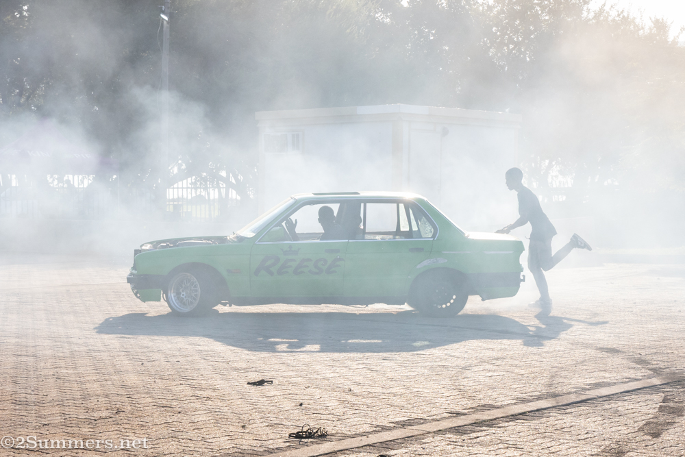 Guy running behind spin car in smoke