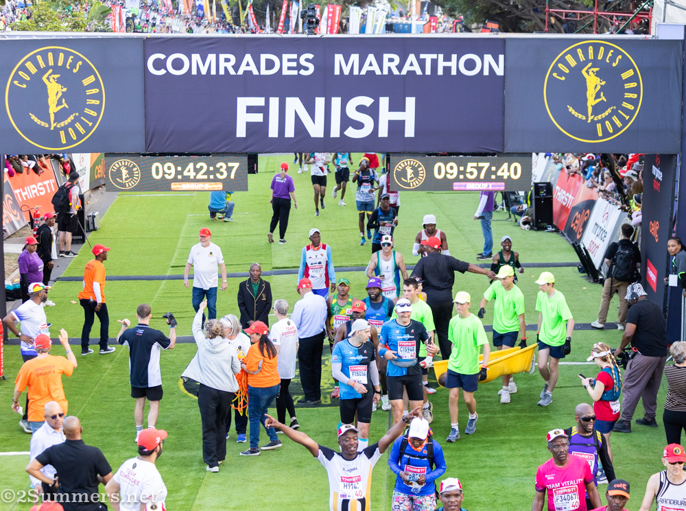The stretcher bearers carry someone off as others finish the race.